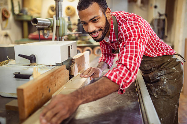 istock Smiling Mid Adult Carpenter Adjusting Wood Piece in Workshop 2251988689