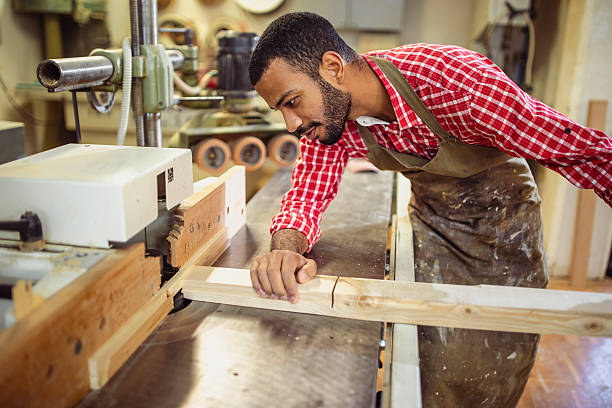 istock Attentive Artisan Shaping Wood Plank in Busy Workshop 2251988693