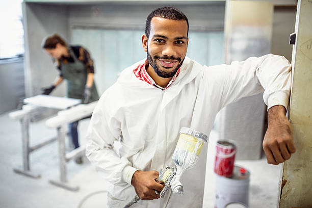 istock Joyful Multiracial Male Using Paint Spray Gun in Workshop 2251988737