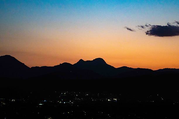 This dramatic landscape shows intense sunset colours spreading across the sky as black mountain silhouettes form a striking contrast along the horizon