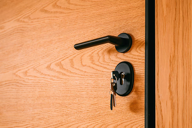 istock Sleek matte-black door handle and keyhole with a set of keys hanging inside 2251991693