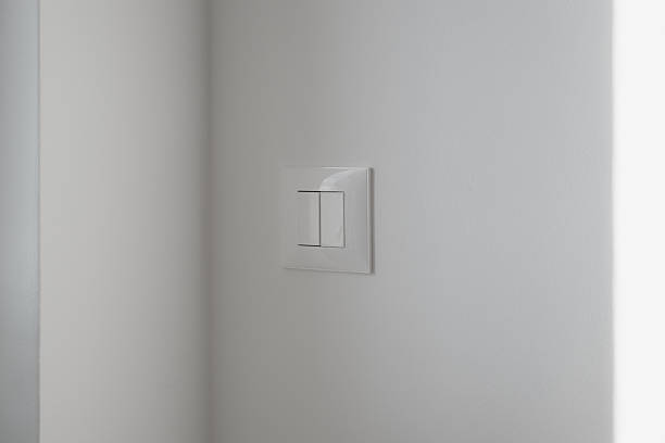 istock Close-up of a sleek white double rocker light switch mounted on a smooth light-gray wall. 2251991777