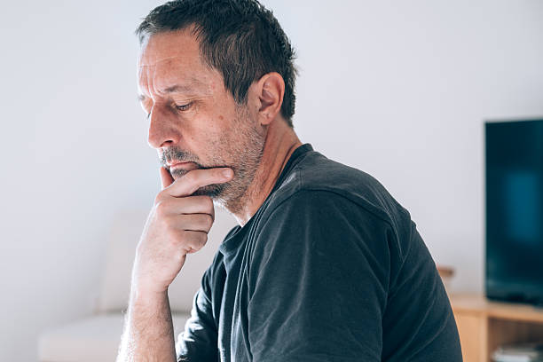 istock Authentic middle-aged caucasian man sitting in profile, hand on chin, looking deeply thoughtful and worried. 2251991840