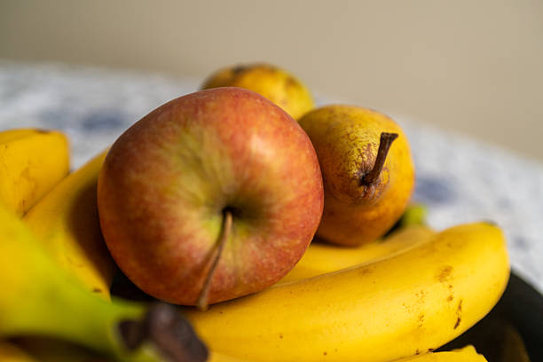 Yellow bananas, green pear and red apple on black background