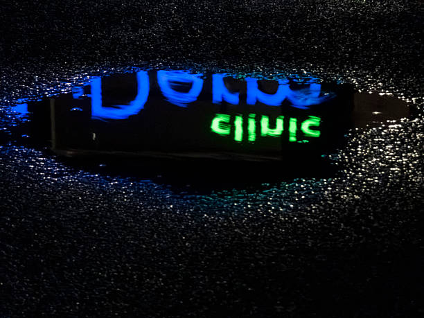 istock Wet asphalt reflecting neon clinic sign at night 2251994466