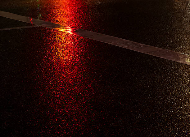 istock Night street wet asphalt reflecting red traffic light 2251994783