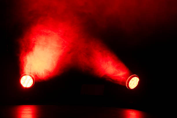 Red lights shine through thick smoke in a dark room during a performance