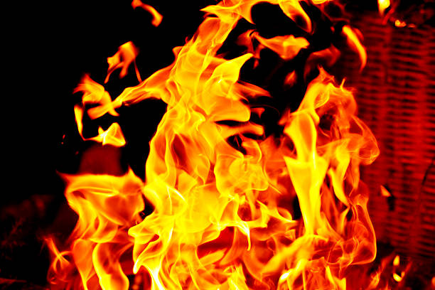 Large burning flames in vibrant yellow and red colors standing out against a dark black background. The image conveys intensity, heat, danger, and dramatic contrast. Suitable for concepts such as fire, energy, power, emergency, risk, destruction, or abstract backgrounds.