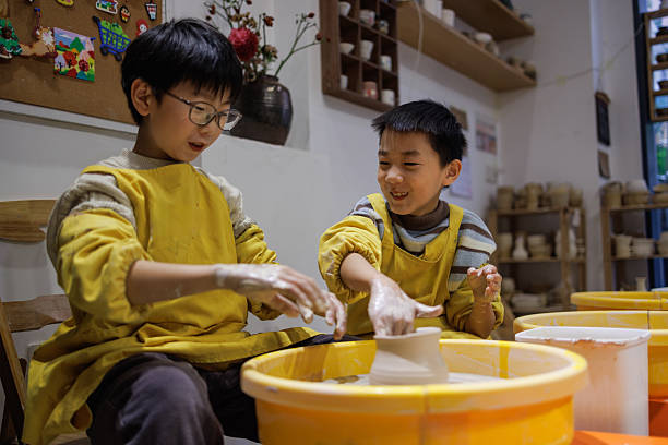 Close-up of hands carefully forming a clay pot on a spinning wheel.  The process of pottery creation.