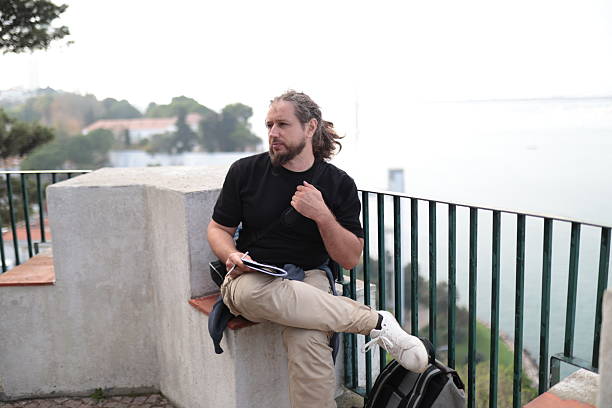 istock Thoughtful male writer taking notes sitting on viewpoint in lisbon 2252000943