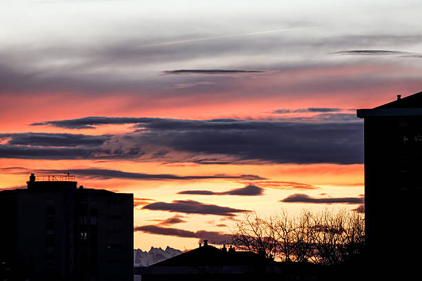 Dramatic Sunset Over Mountain Silhouette, Vibrant Sky with Fiery Clouds and Urban Shadow