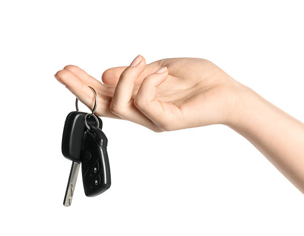 Woman with car keys on white background, closeup