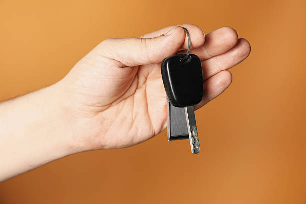 istock Man with car key and keychain on orange background, closeup 2252003922