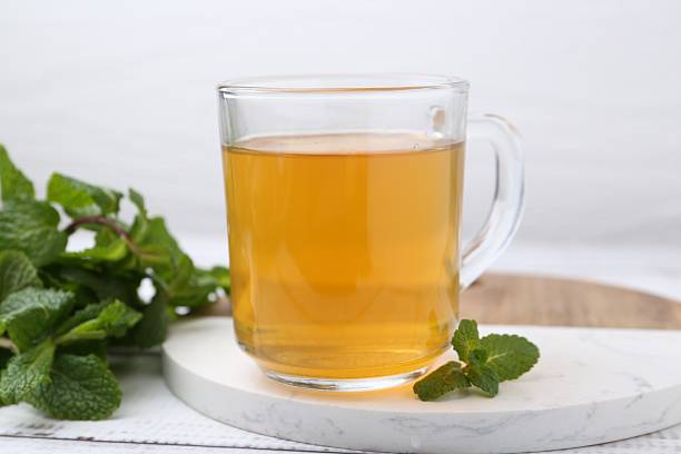 istock Aromatic mint tea and fresh leaves on white wooden table, closeup 2252008683