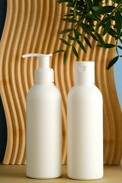 istock Two white cosmetic bottles with pump and flip-top cap on wave wooden background 2252012115
