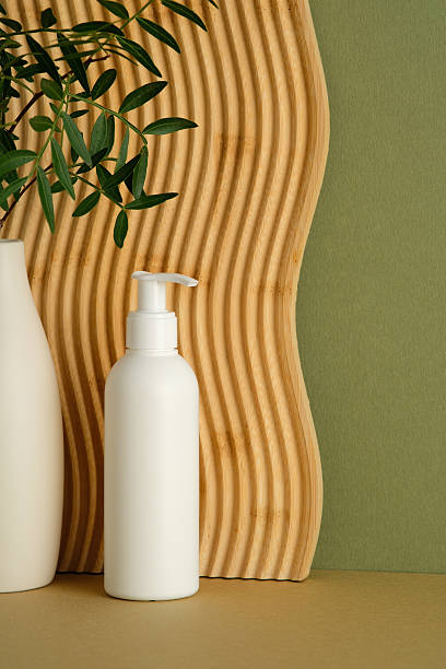 istock White lotion pump bottle next to a curved wooden panel and green leaves. 2252012199