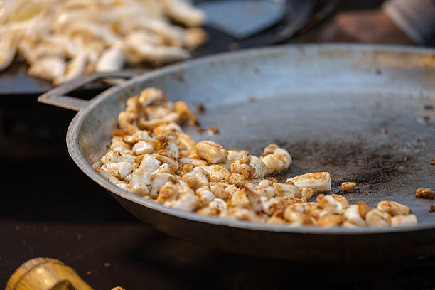 Asian street food market stall, fishes are cooking on pan at night market.