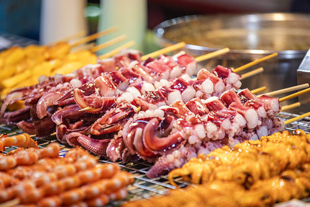 Asian street food market.Seafood (octopus) skewers sales on street food market stand.Phuket Island - Thailand.