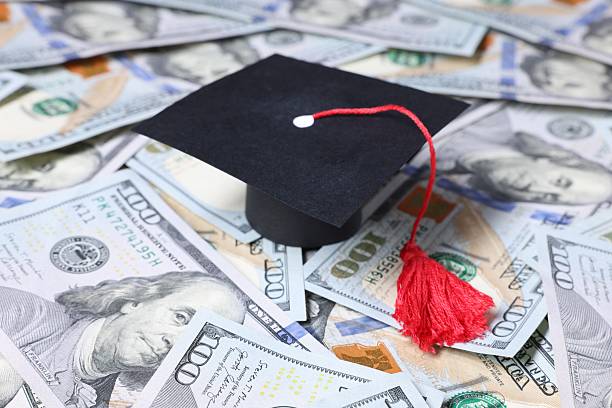 istock Graduate hat and dollars on table. Tuition payment 2252013828
