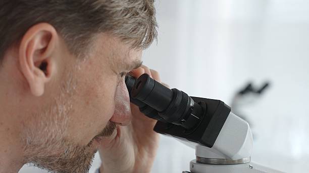 istock Close up of a man scientist carefully observing through a microscope in a brightly lit laboratory, conducting research for developing new medicines and treatments. Medicine and science concept 2252014332