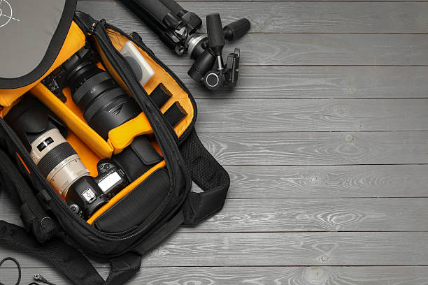 Professional photographer's equipment and backpack on grey wooden background, flat lay. Space for text