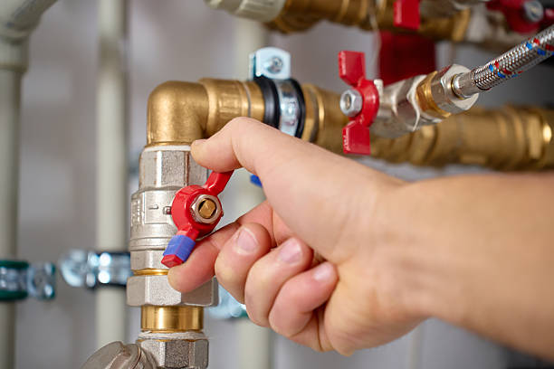 istock Technician adjusting valve on heat pump piping system close up 2252019209