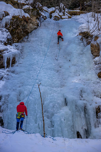 Imst Pitztal, Austria - 02 February 2024: Ice climbers ascending frozen waterfall with technical tools and ropes vertical ice wall winter mountaineering sport extreme outdoor activity in alpine environment