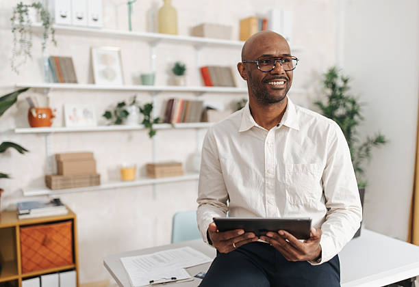istock Man Holding Tablet, Smiling Comfortably at Home 2252030273