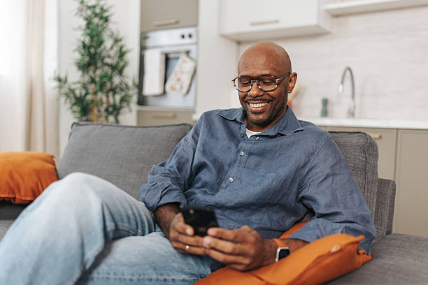 istock Laughing Man Enjoying His Phone on Couch 2252030914