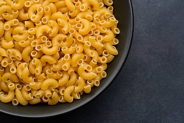 istock Raw macaroni pasta on black stone background 2252031358