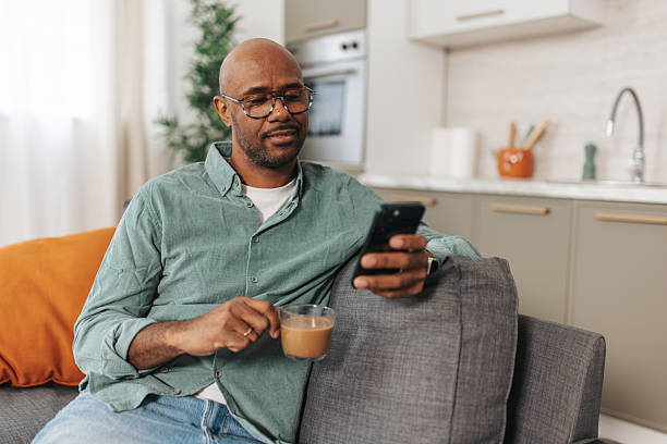 istock Man enjoying coffee while checking phone at home 2252031714