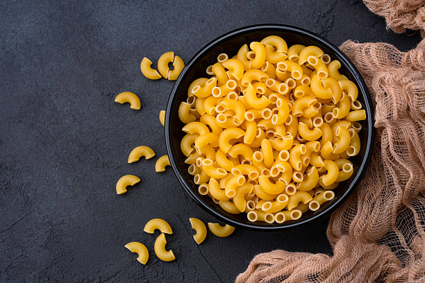 istock Raw macaroni pasta on black stone background 2252032261