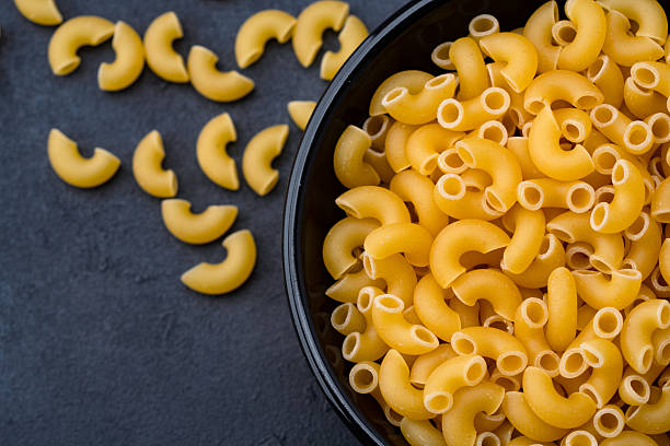 istock Raw macaroni pasta on black stone background 2252032276