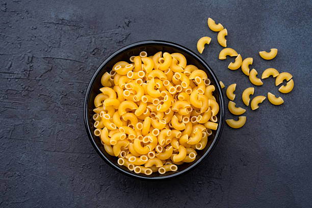 istock Raw macaroni pasta on black stone background 2252032316