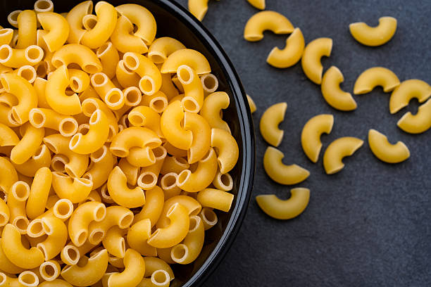 istock Raw macaroni pasta on black stone background 2252032380