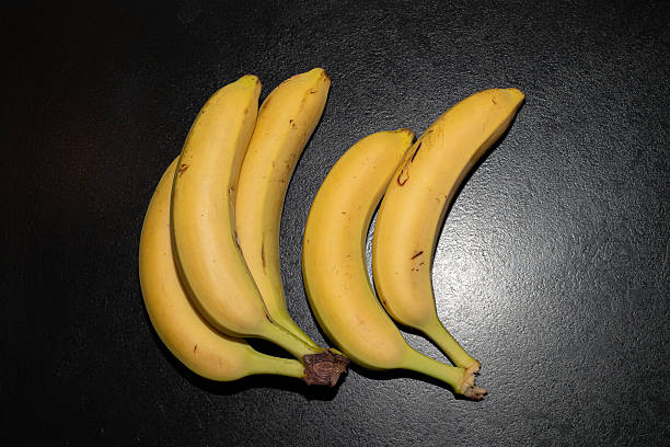 istock Ripe single banana arranged on black background, modern art banana fruit on black table 2252041187