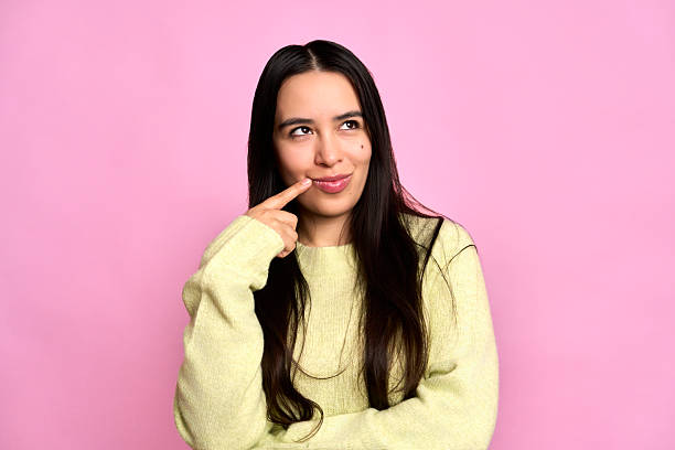 istock Young woman thinking looking up with finger on lips 2252041775