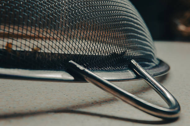 Abstract macro composition of large kitchen metal sieve on table.