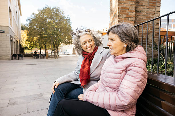 istock Senior women friends sharing conversation on park bench 2252048792