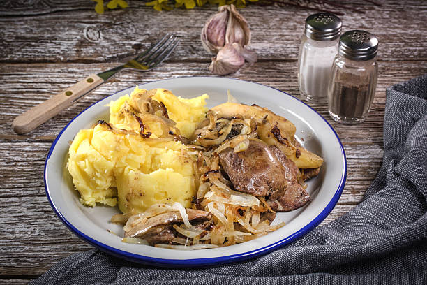 Fried liver with onion and apple, served with boiled potatoes and pickled cucumber.