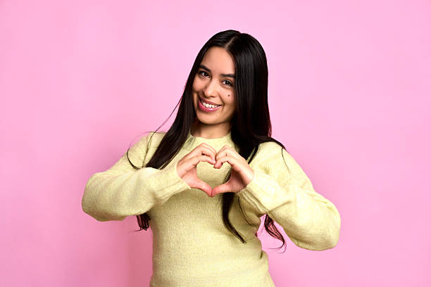 istock Young woman smiling forming heart shape with hands 2252051899