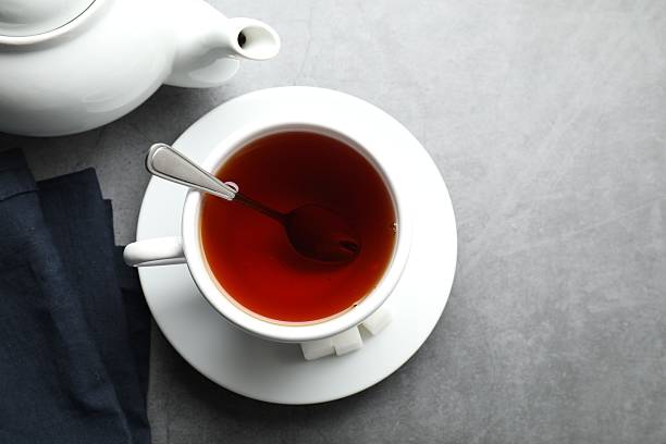 istock Refreshing black tea in cup, sugar cubes and teapot on grey textured table, flat lay. Space for text 2252052882