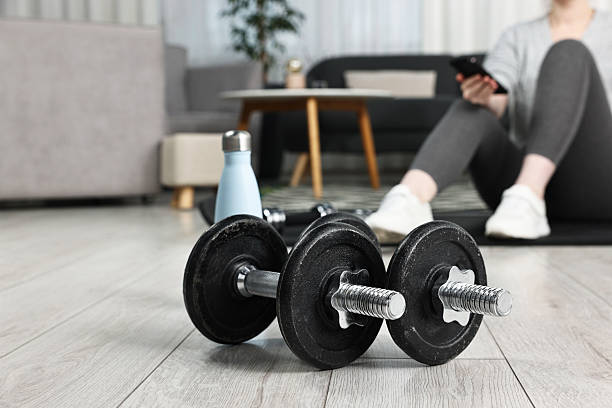 istock Woman with smartphone indoors, focus on barbells 2252054504