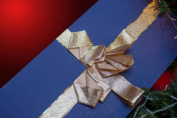 A wrapped gift box in peach color color adorned with a blue ribbon, set against a white background. color trend 2024.