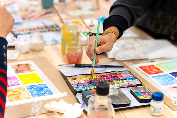 istock Hand dipping brush in watercolor palette during art workshop 2252055236