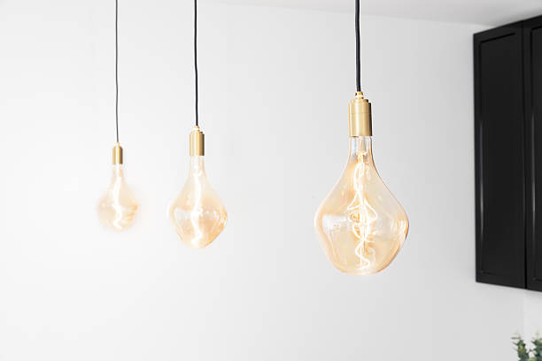 istock Three Edison Style Light Bulbs Hang Down From Ceiling With Warm Amber Glow In Minimalist Interior Design Setting 2252055859