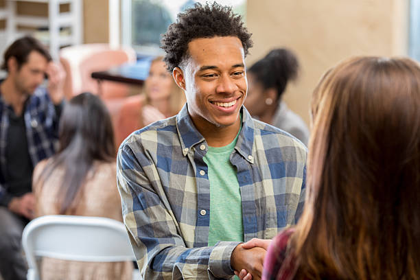 istock Young man confidently shakes hands with someone during a group meeting or support session. 2252056099