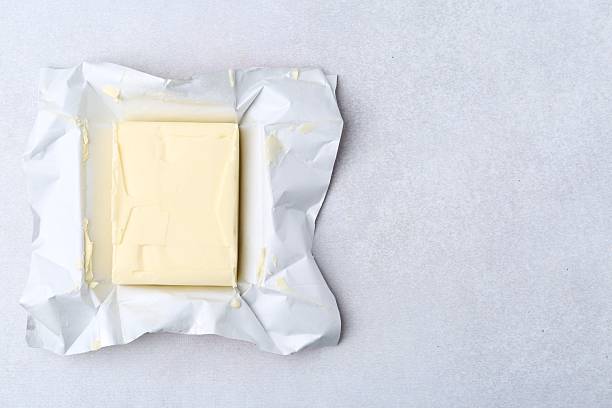 istock Block of tasty butter in open package on light grey table, top view. Space for text 2252057586