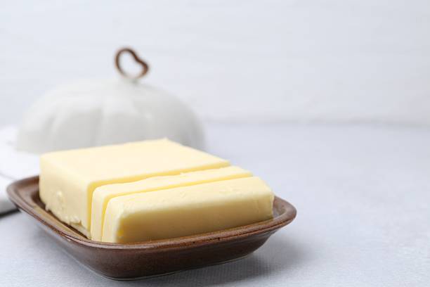 Cut tasty butter in dish on light grey table, closeup. Space for text