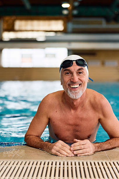 istock Senior man smiling in swimming pool wearing swim cap 2252057849